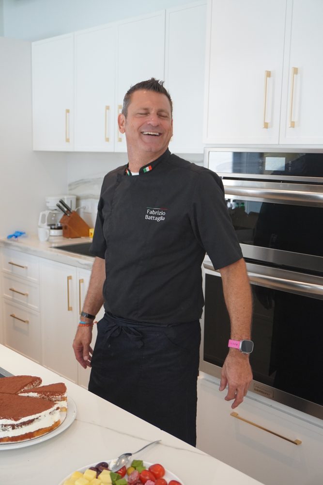Chef Fabrizio laughing in a bright kitchen with a tiramisu on the counter