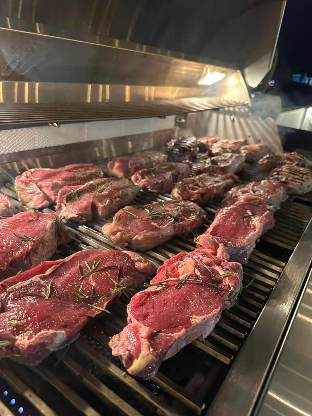 Steaks with rosemary cooking on a barbecue grill